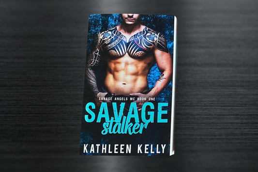 A signed paperback book titled 'Savage Stalker' by Kathleen Kelly with a foiled teal title on the cover.